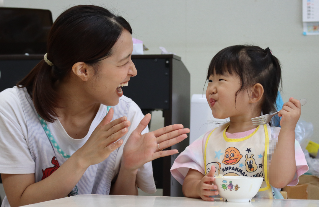 給食の時間に先生と笑い合う園児