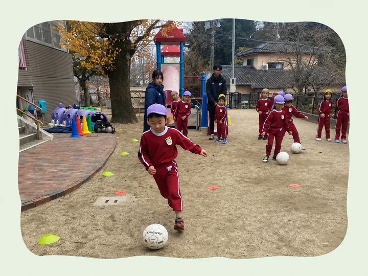 園庭でサッカー教室に参加する園児たち