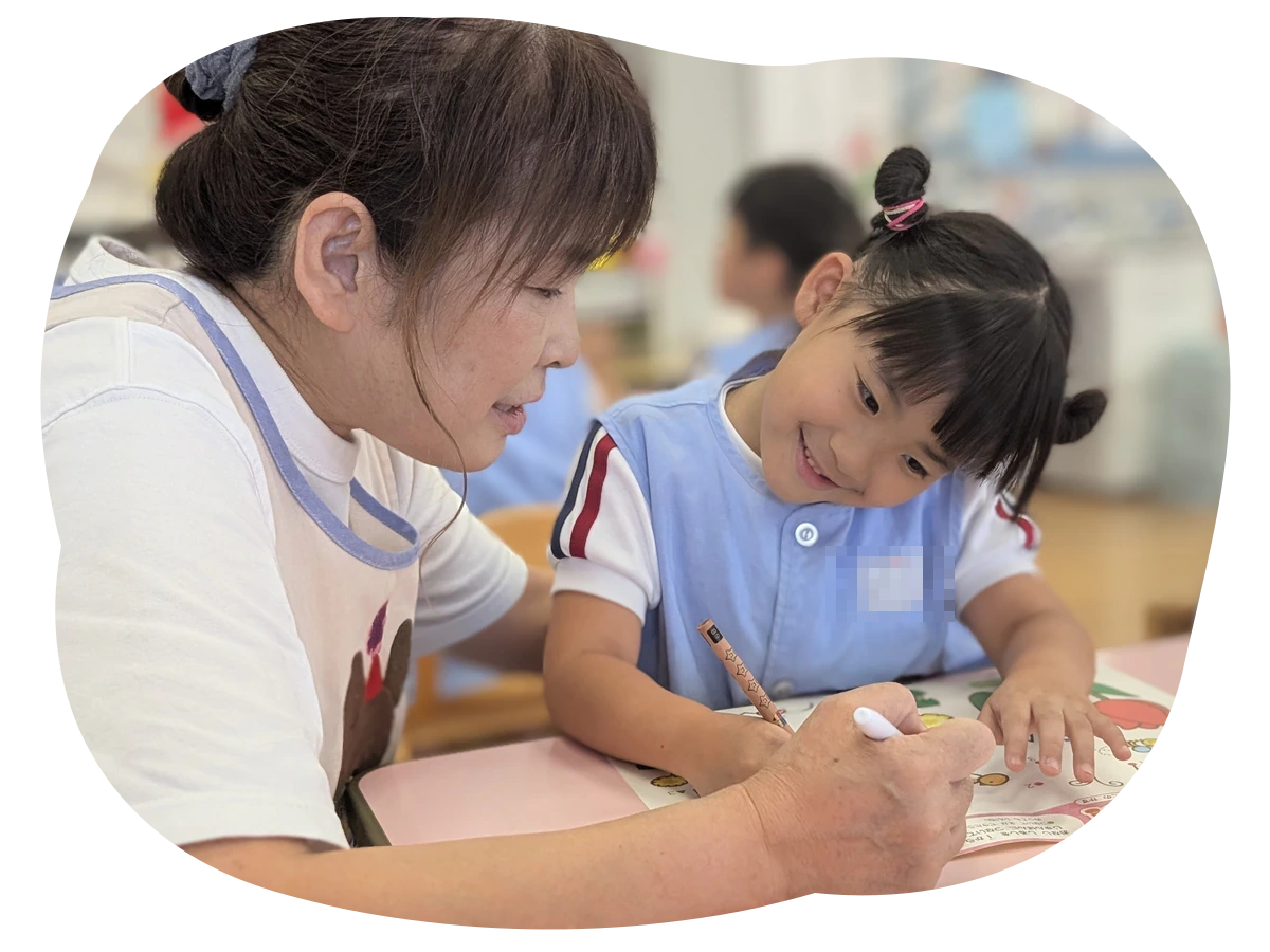 先生と一緒に書き方へ取り組む園児