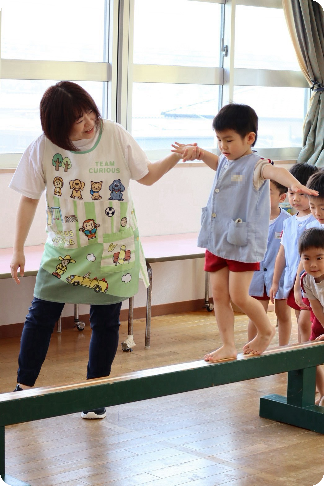 平均台に取り組む子どもと見守る保育士