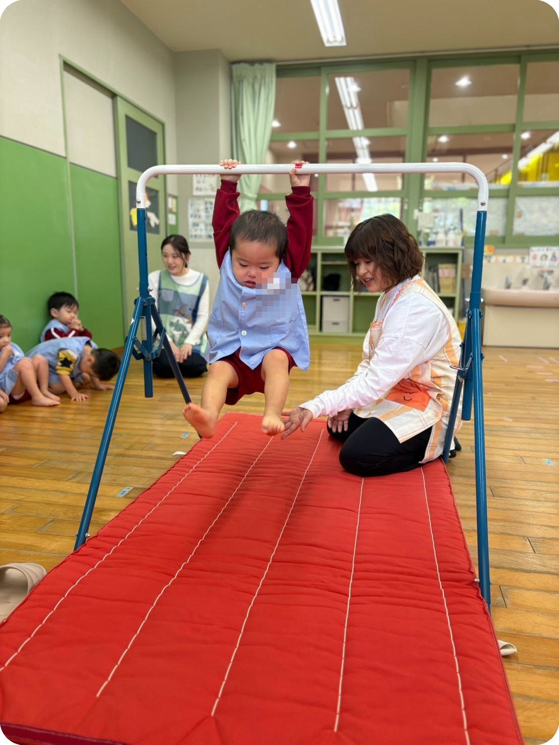 鉄棒に取り組む子どもを見守る保育士