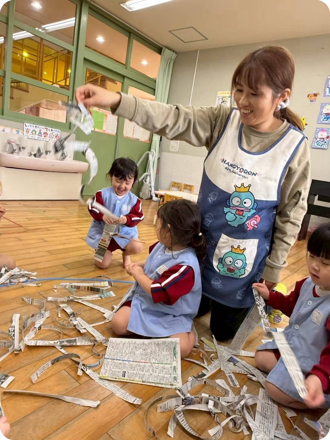 新聞紙遊びをする保育士と子どもたち