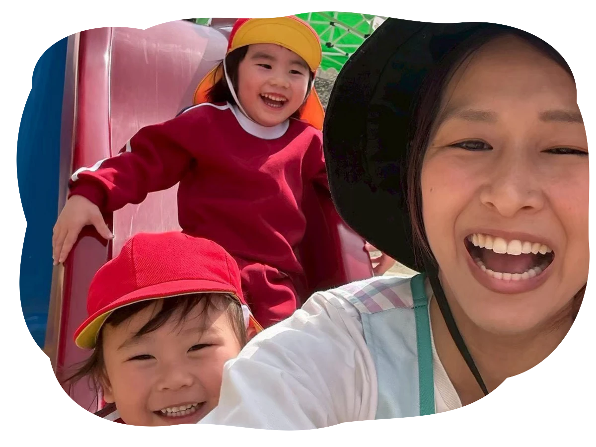 滑り台で先生と園児が笑顔で撮影している様子