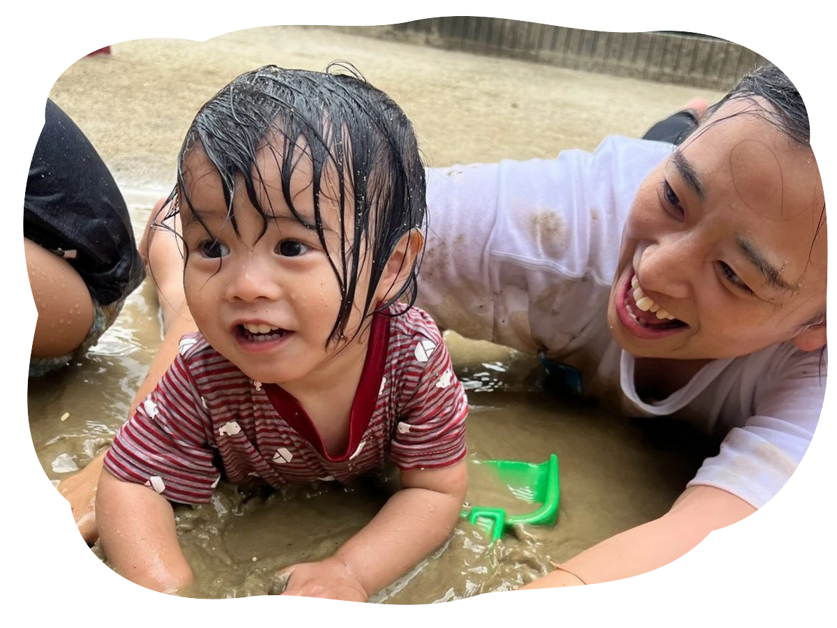 先生と園児が園庭で泥遊びを楽しんでいる様子