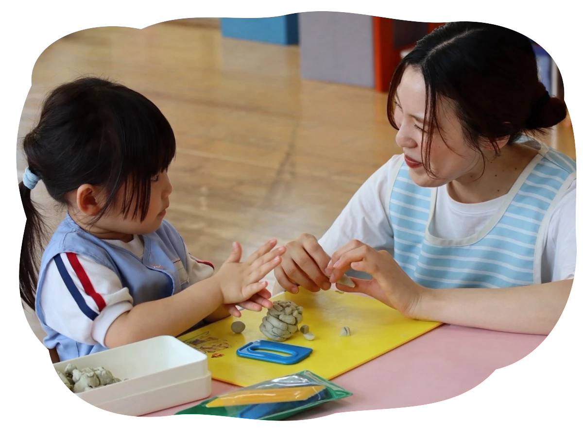 先生と園児がテーブルで粘土遊びをしている様子