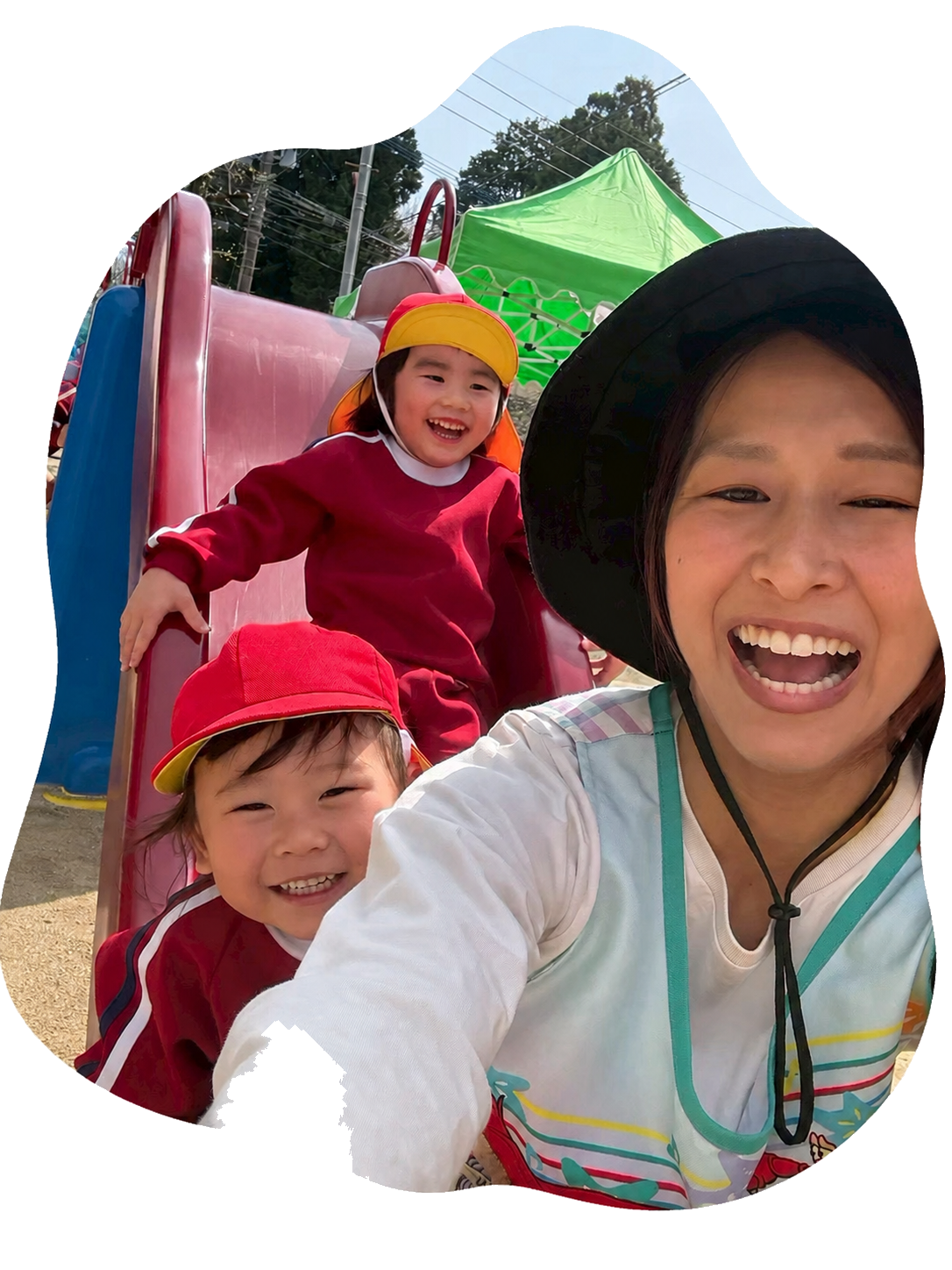 滑り台で遊ぶ園児たちと保育士の記念写真