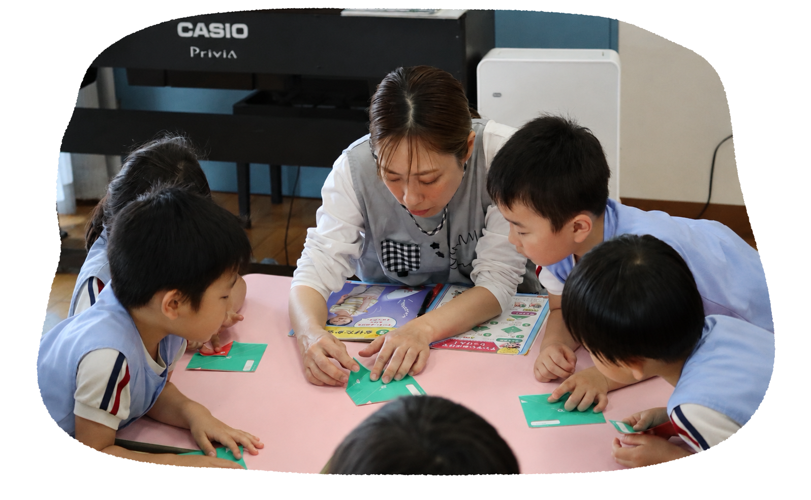 折り紙遊びをする子どもたちと保育士
